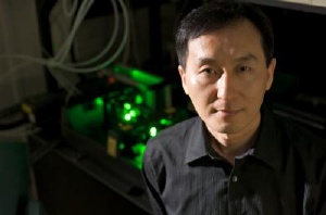 Chunlei Guo stands in front of his femtosecond laser, which can double the efficiency of a regular incandescent light bulb. Credit: University of Rochester