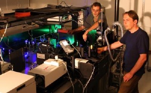 University of Utah physicists John Lupton and Christoph Boehme use green and blue laser beams to "excite" a small piece of an organic or "plastic" polymer (glowing orange near Boehme