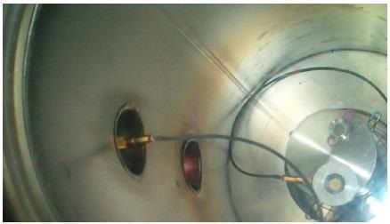 Interior of chamber #1 showing Evactron plasma pink glow during Evactron cleaning exposure of window #5. A quartz thin film thickness monitor is also shown in the chamber placed on a pedestal beside the window.