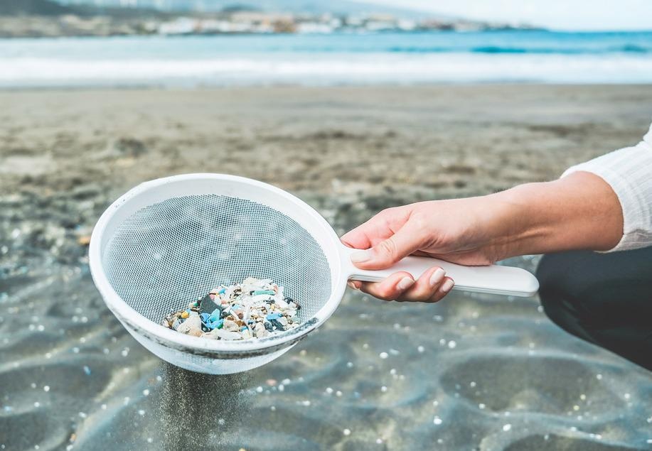 woman cleaning microplastics from ocean sand