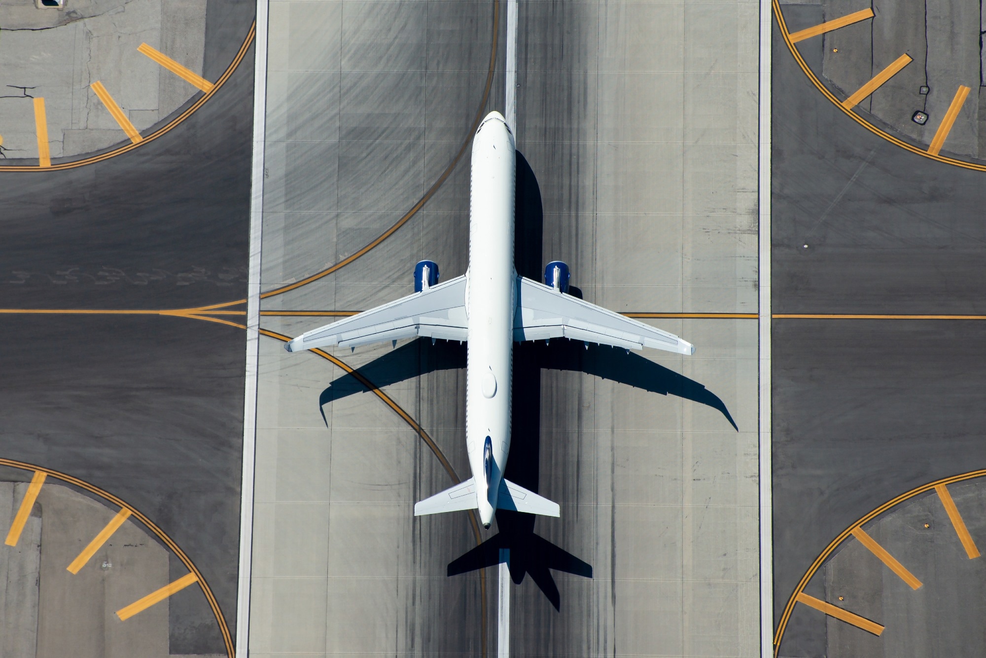 Aerial view of narrow body aircraft departing airport runway.