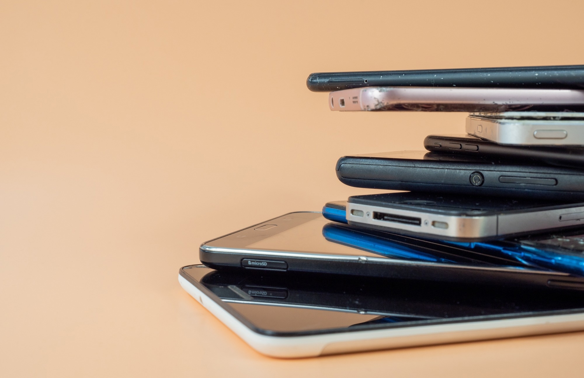 A stack of different phones against an apricot background.