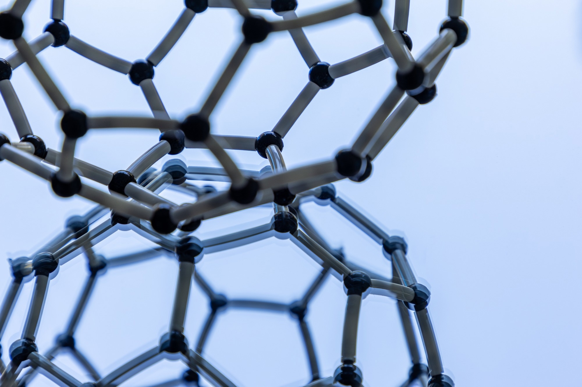 Image of a model of a fullerene particle against a reflective surface.