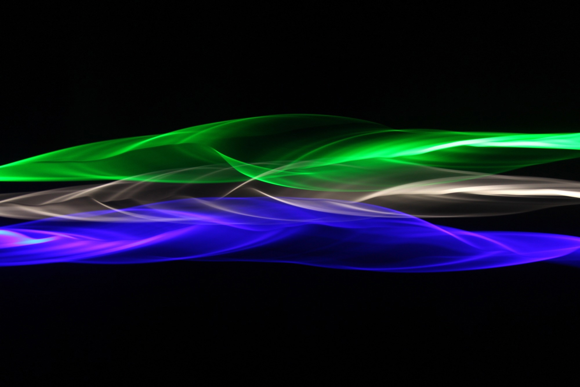 Light scattering across a dark background (blue, white, green) illustrating photonic wave motion.