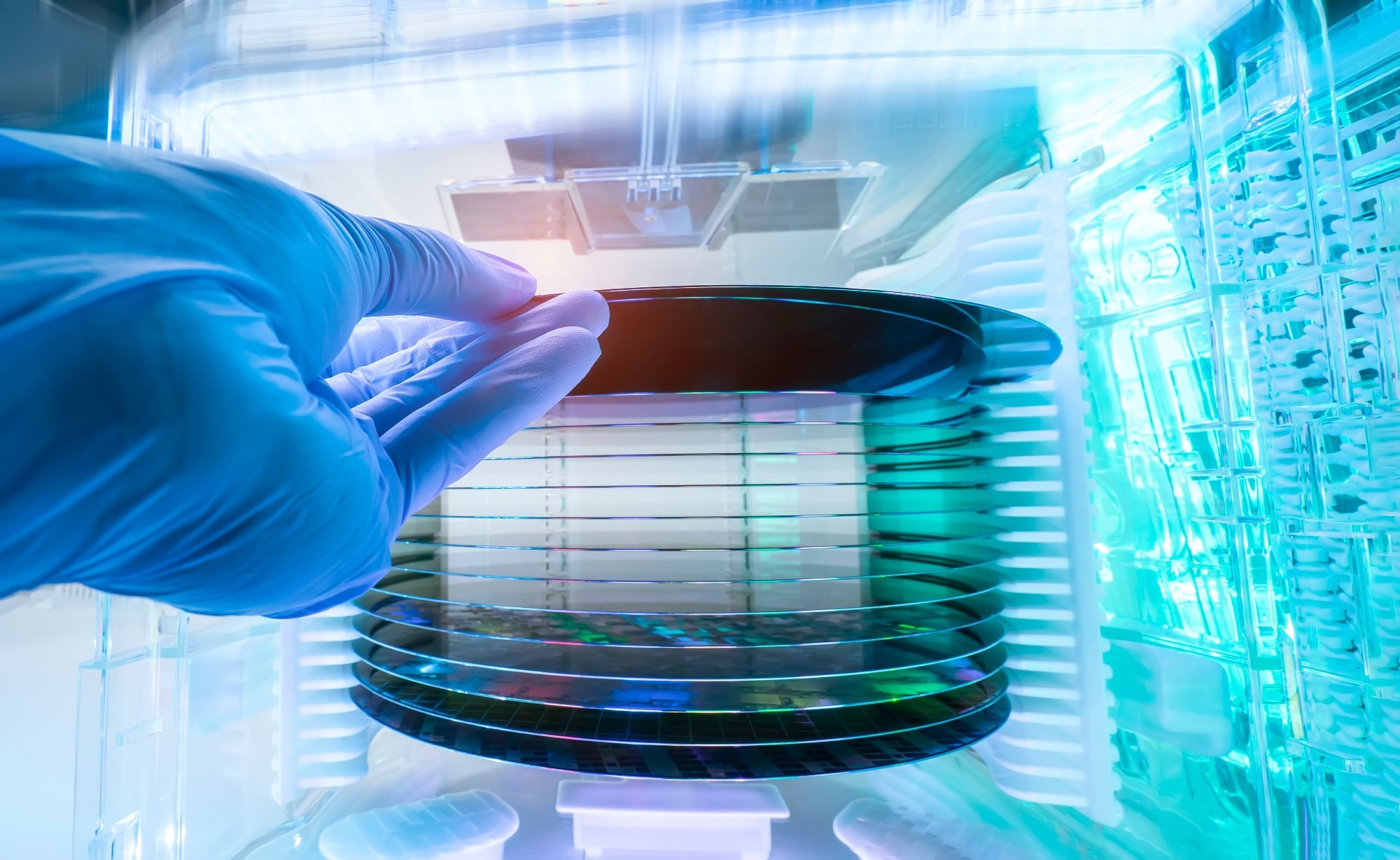 Gloved hand holding a Silicon Wafer in plastic holder box used in electronics for the fabrication of integrated circuits