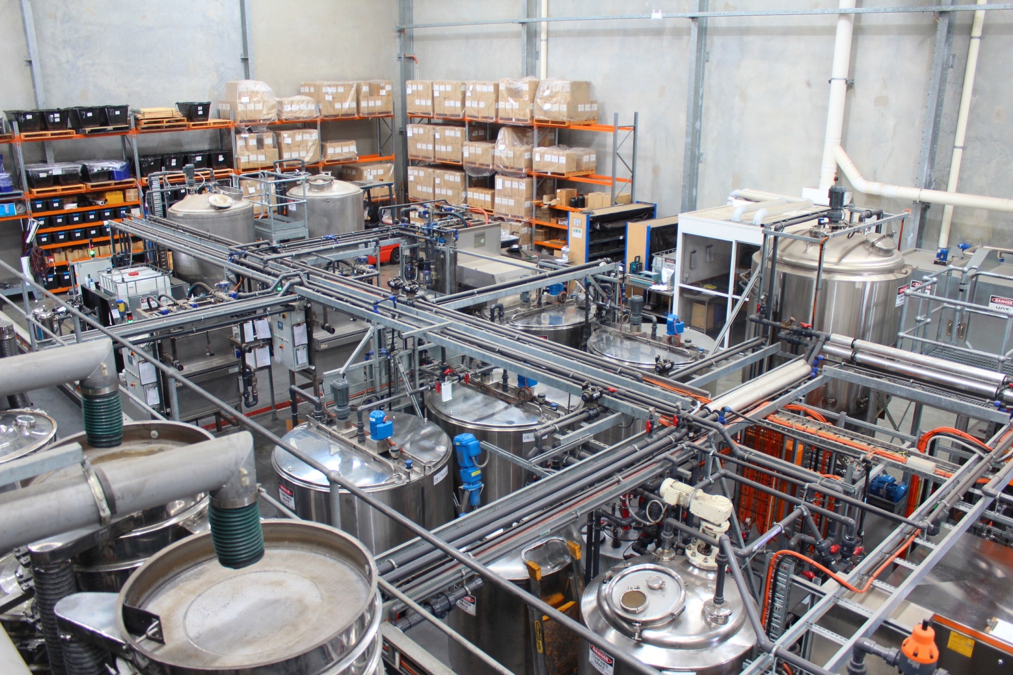 An image of the First Graphene factory process, with a multitude of pipes, pumps, and barrels.