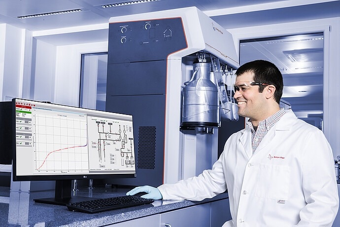 A male Anton Paar scientist wearing a lab coat and goggles reviews spectra obtained from the device.