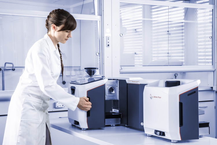 A scientist in a white lab coat removes samples from the DIF analyzer against a white lab background.
