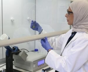 Ph.D. candidate Badriah Alotaibi with a gold chloride solution and the vortex fluidic device used in the research experiments