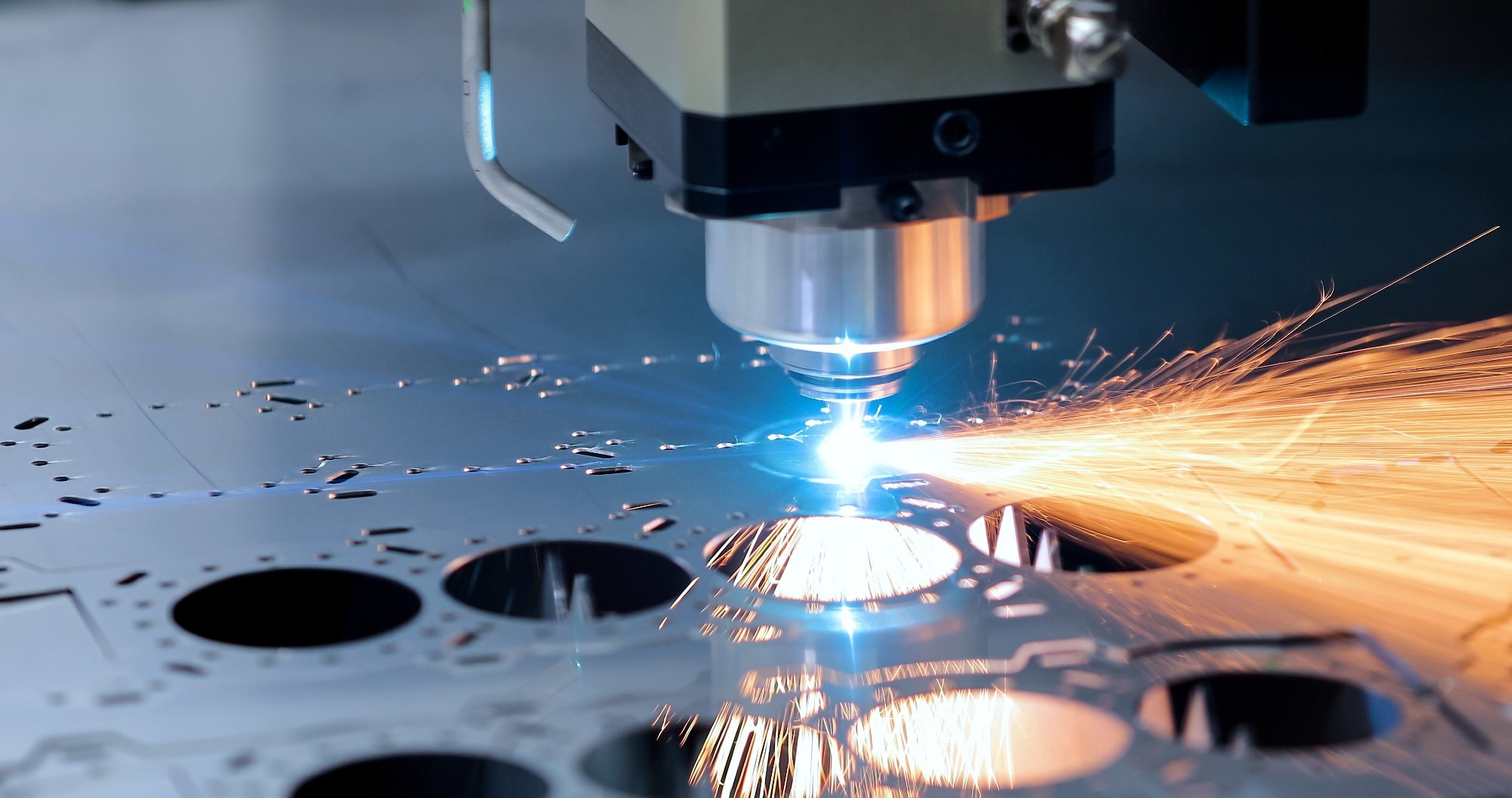 Close-up of a high-precision laser cutting machine slicing through sheet metal, producing bright sparks and intricate patterns
