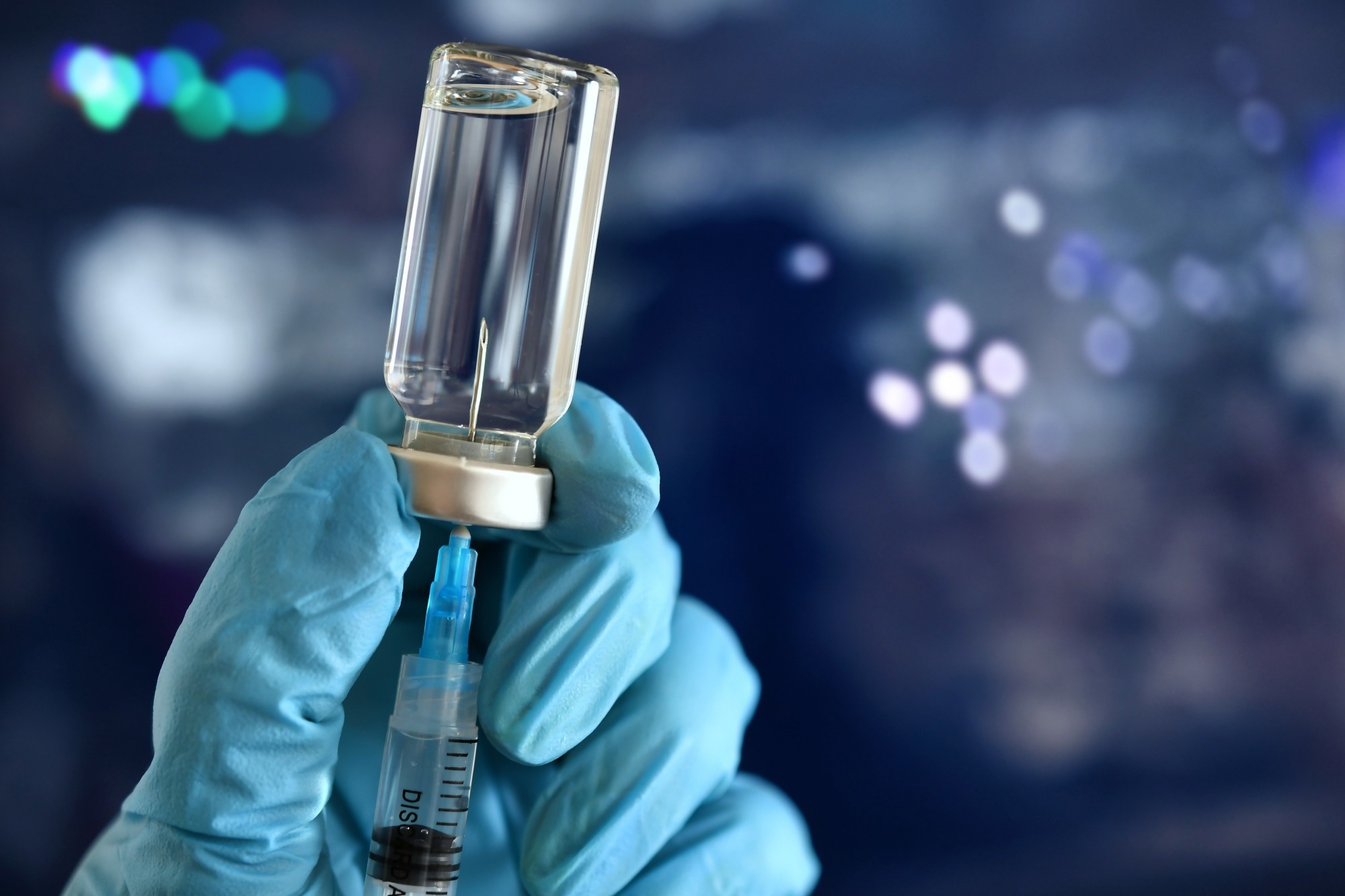 Medical personnel filling a syringe needle with generic vaccine booster