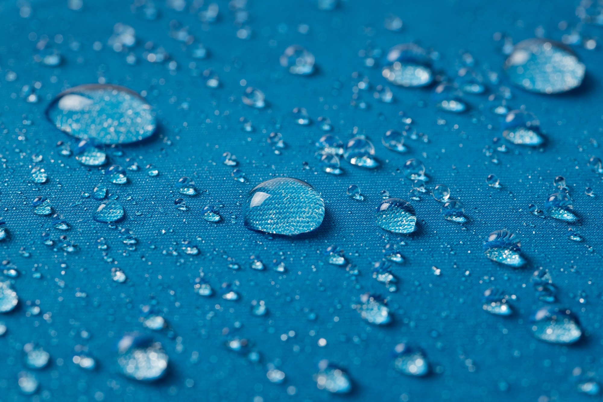 Hydrophobic blue surface with water droplets collecting on top, indicating its hydrophobicity.